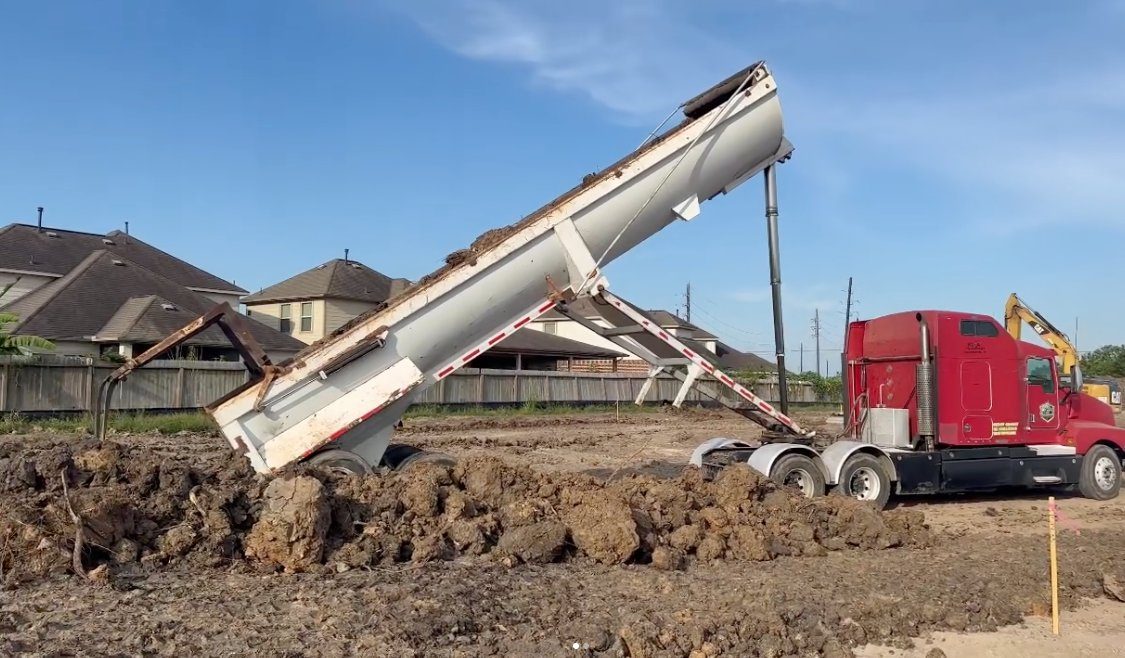Supreme Logistics end dump trailer placing fill on a Greater Houston residential jobsite